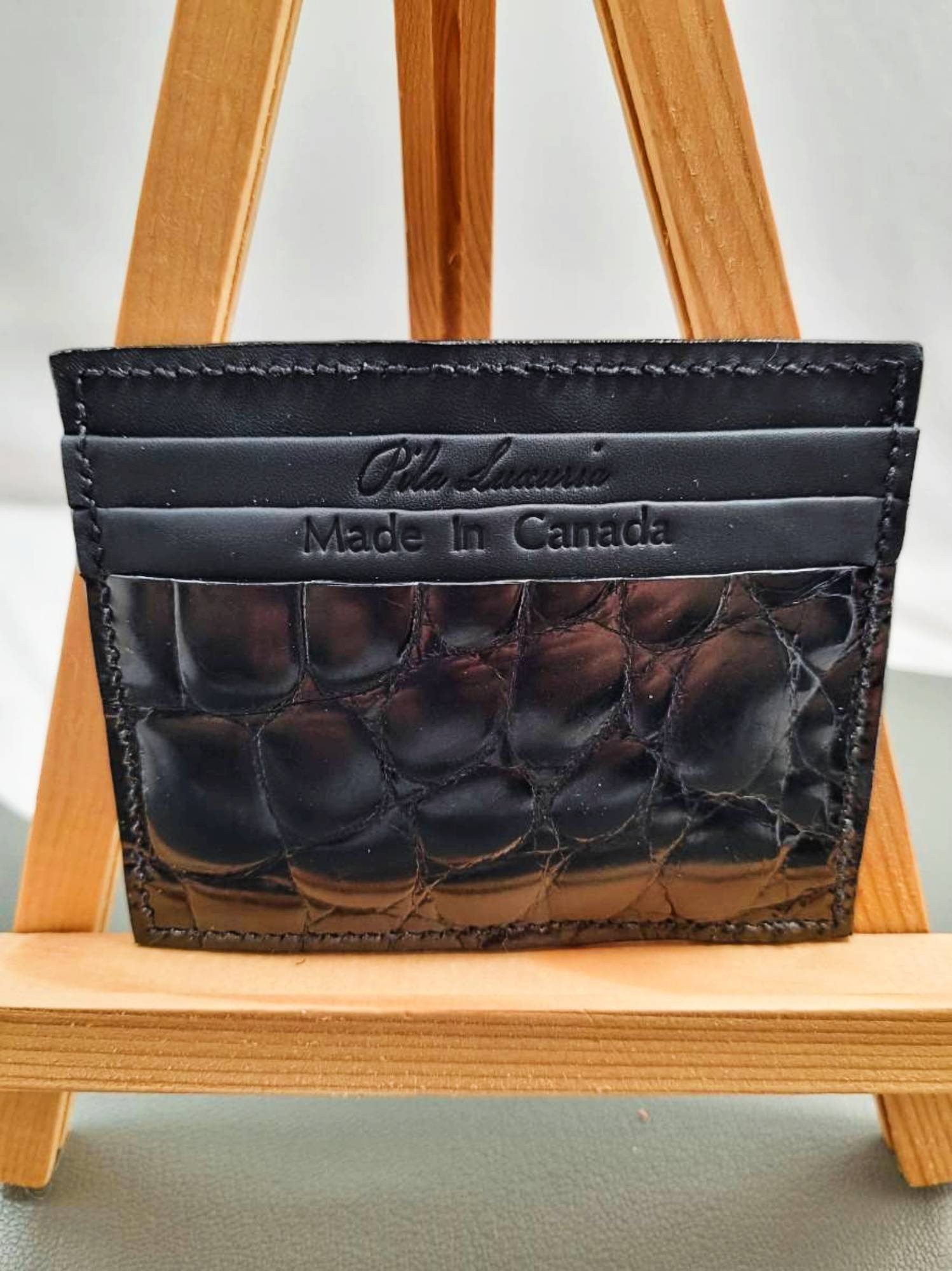 Black mirror finish crocodile leather card holder made by Pila Luxuria in Canada shown from the front.