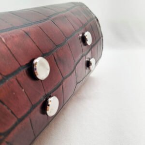 The base bag feet of an exotic red alligator leather handbag made by Pila Luxuria in Alberta, Canada.