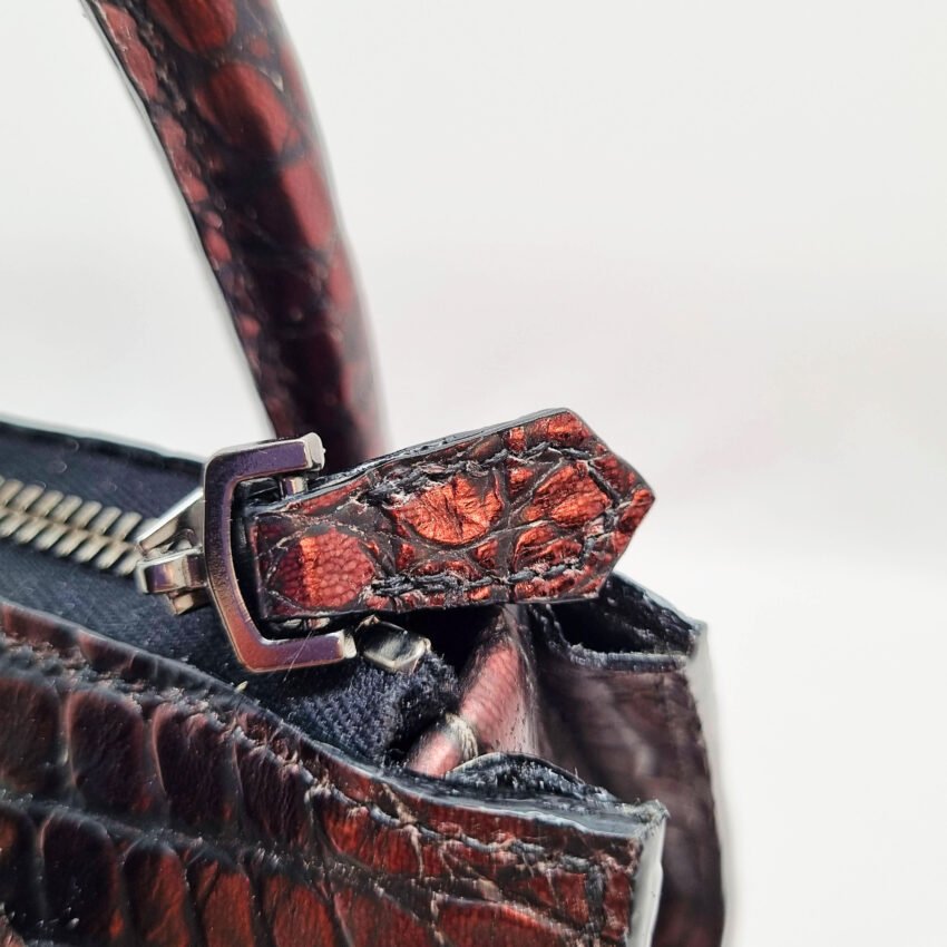 The zipper of an exotic red alligator leather handbag made by Pila Luxuria in Alberta, Canada.