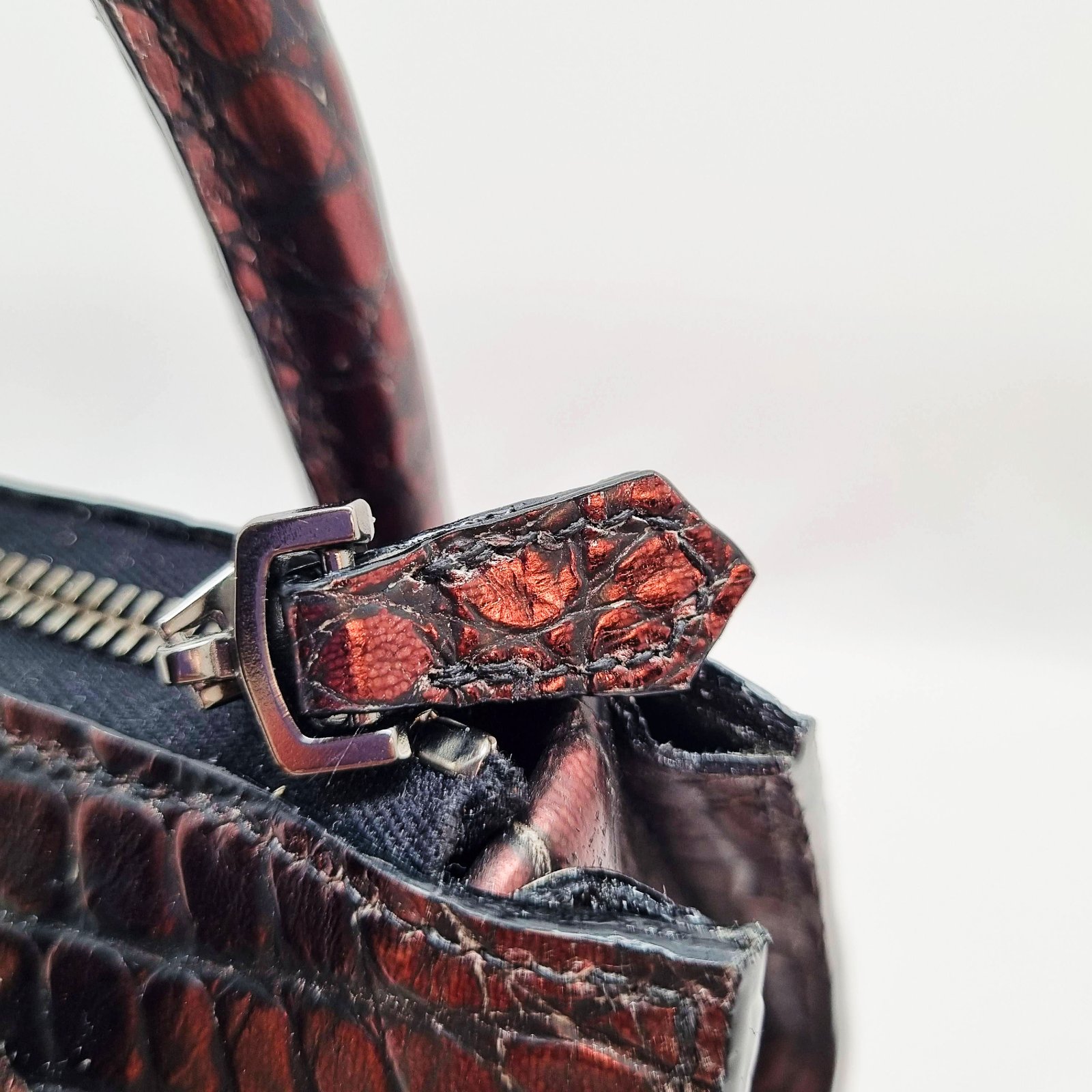 The zipper of an exotic red alligator leather handbag made by Pila Luxuria in Alberta, Canada.