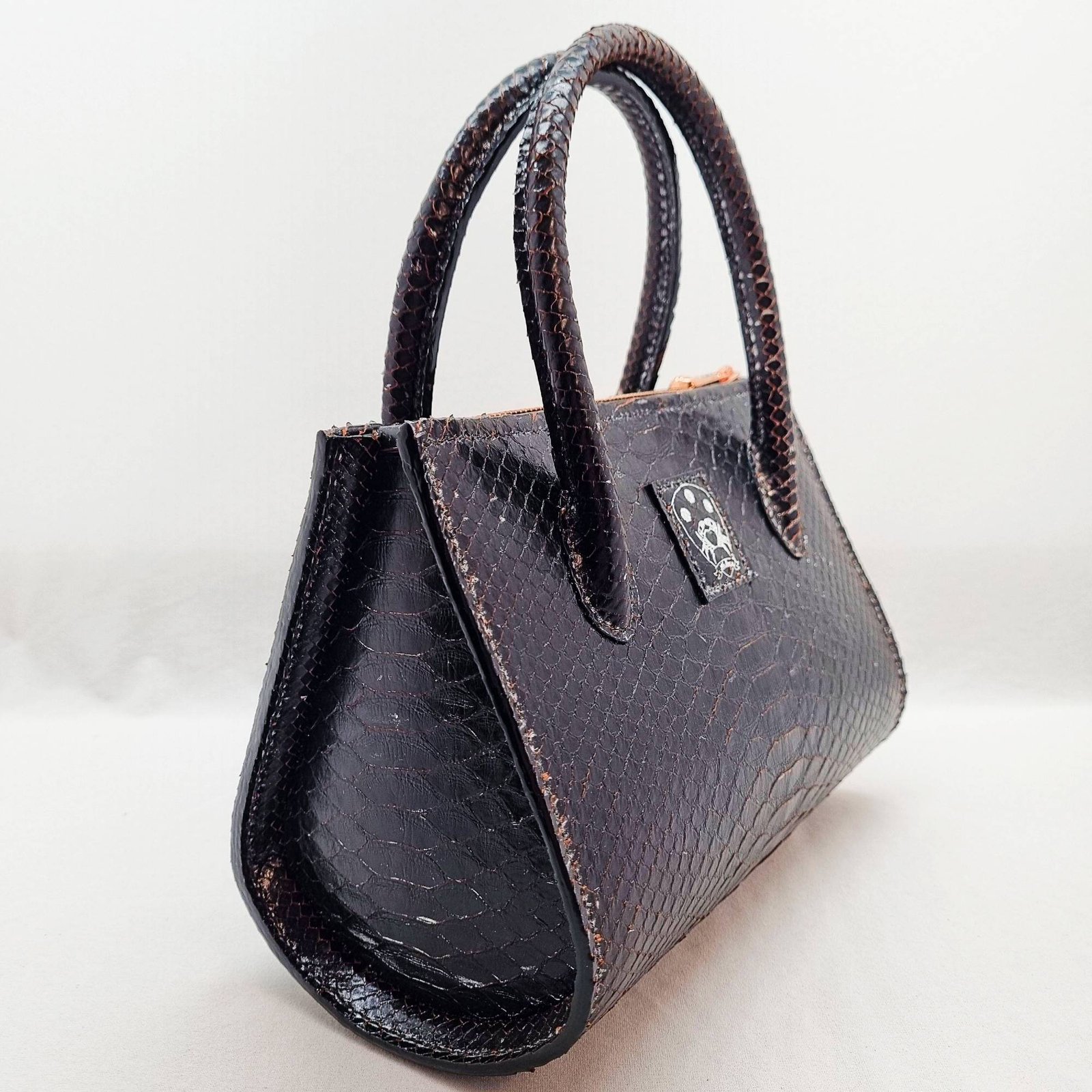 An exotic black python leather handbag made by Pila Luxuria in Alberta, Canada shown from a front angle.