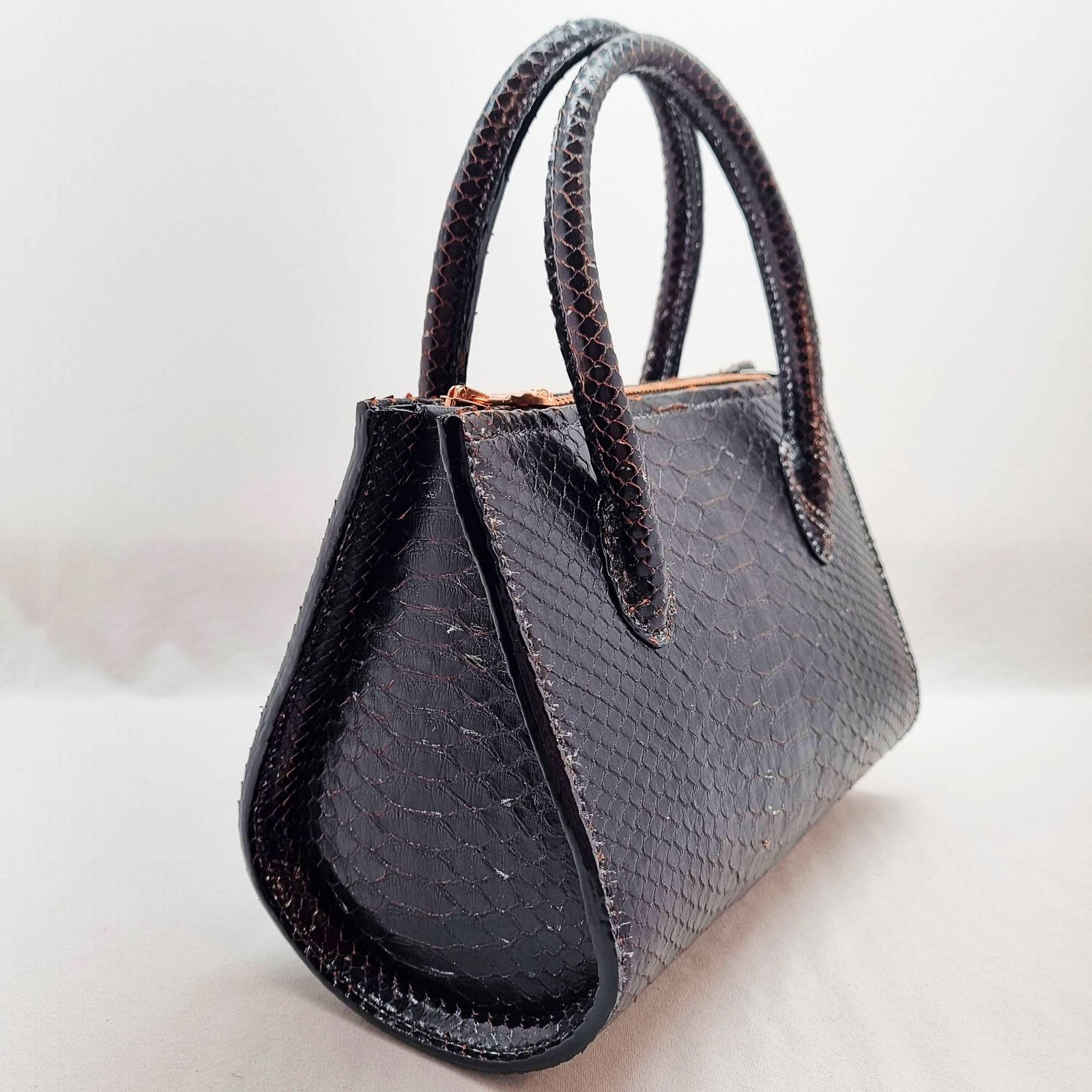 An exotic black python leather handbag made by Pila Luxuria in Alberta, Canada shown from an angle.