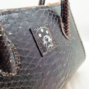 An exotic black python leather handbag made by Pila Luxuria in Alberta, Canada displaying scales and embossed logo.