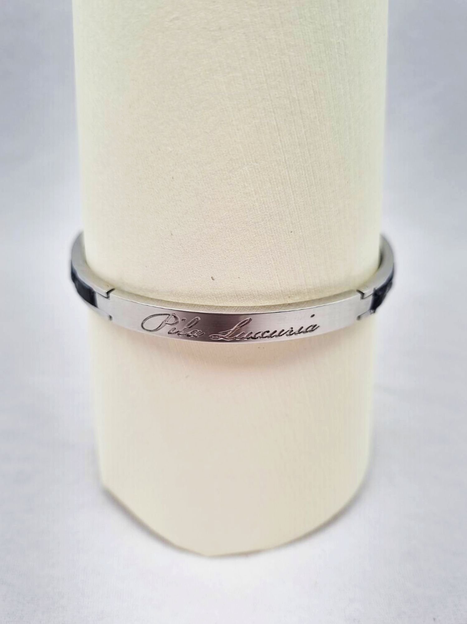 Logo of a luxury black crocodile clasp bracelet, made by Pila Luxuria in Canada.