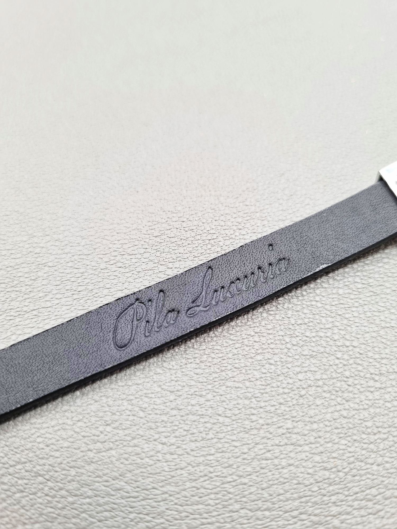 Embossed logo of a luxury black epi leather bracelet with a magnetic clasp, made by Pila Luxuria in Canada.