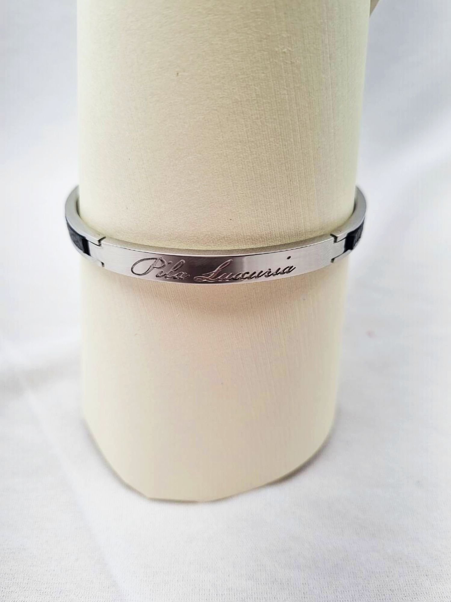 Logo of a luxury black epsom clasp bracelet, made by Pila Luxuria in Canada.