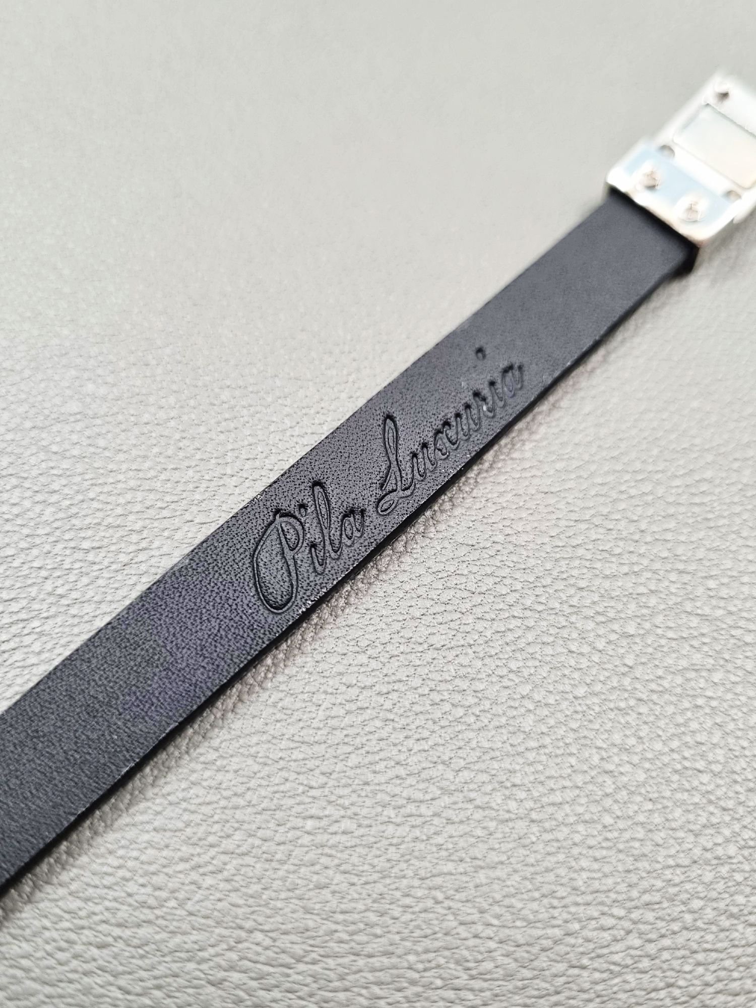 Embossed logo of a luxury tarnished python leather bracelet with a magnetic clasp, made by Pila Luxuria in Canada.