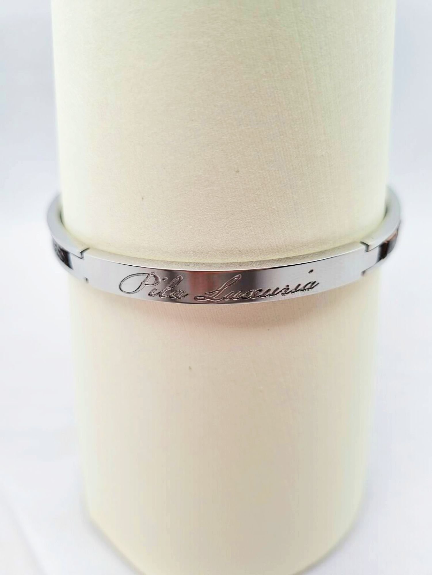 Logo of a luxury brown ostrich clasp bracelet, made by Pila Luxuria in Canada.