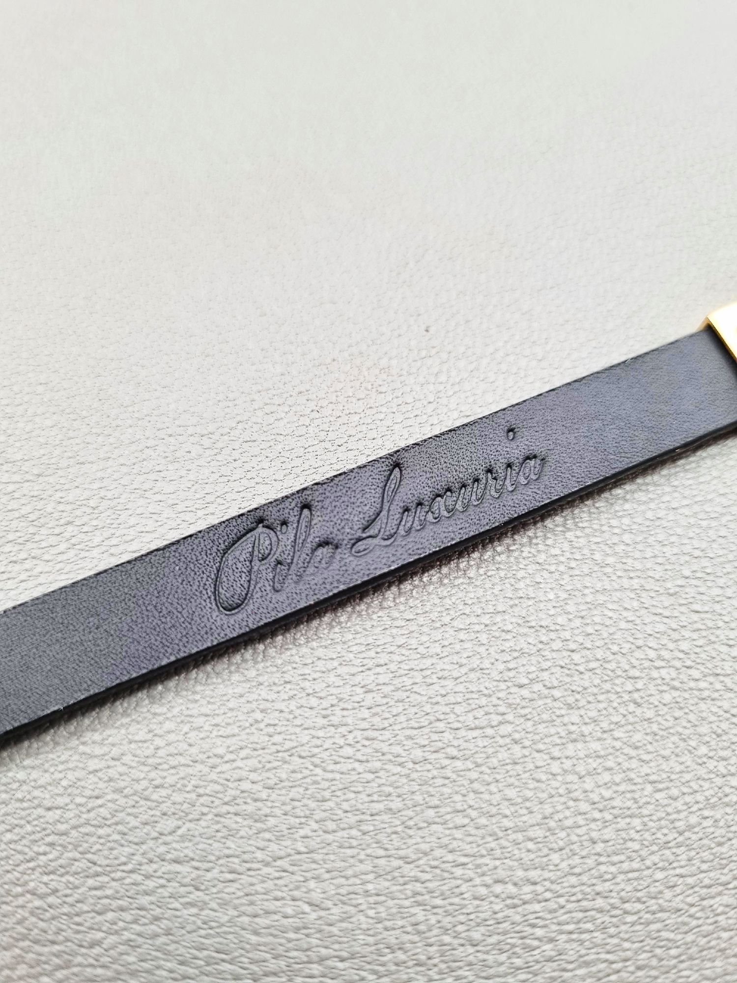 Embossed logo of a luxury brushed gold crocodile leather bracelet with a magnetic clasp, made by Pila Luxuria in Canada.