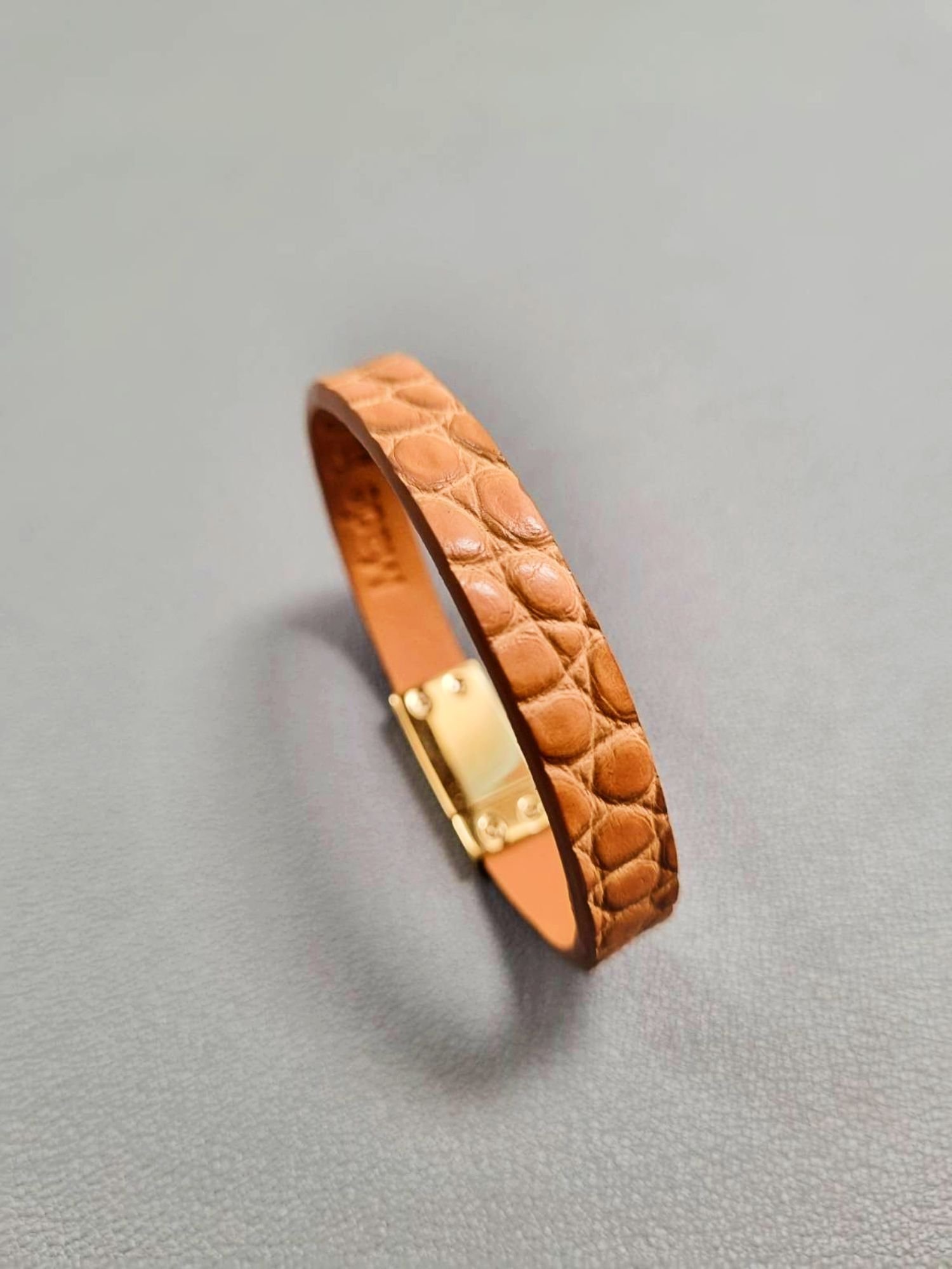 Angled view of a luxury cognac crocodile bracelet with a magnetic clasp, made by Pila Luxuria in Canada.