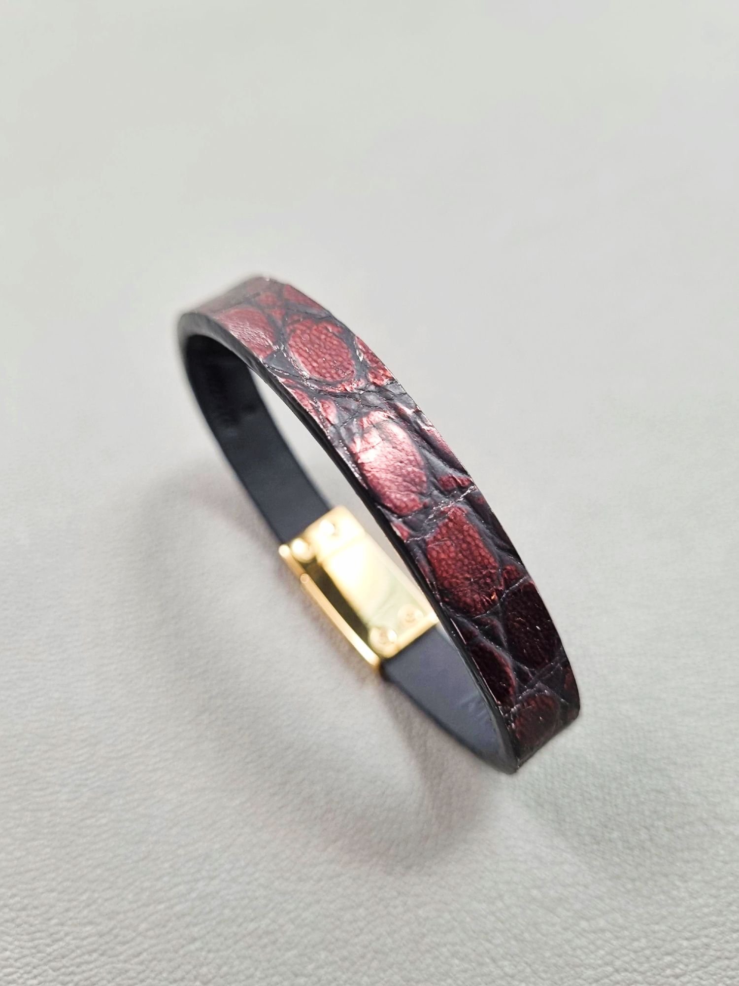 Angled view of a luxury black and red alligator leather bracelet with a magnetic clasp, made by Pila Luxuria in Canada.