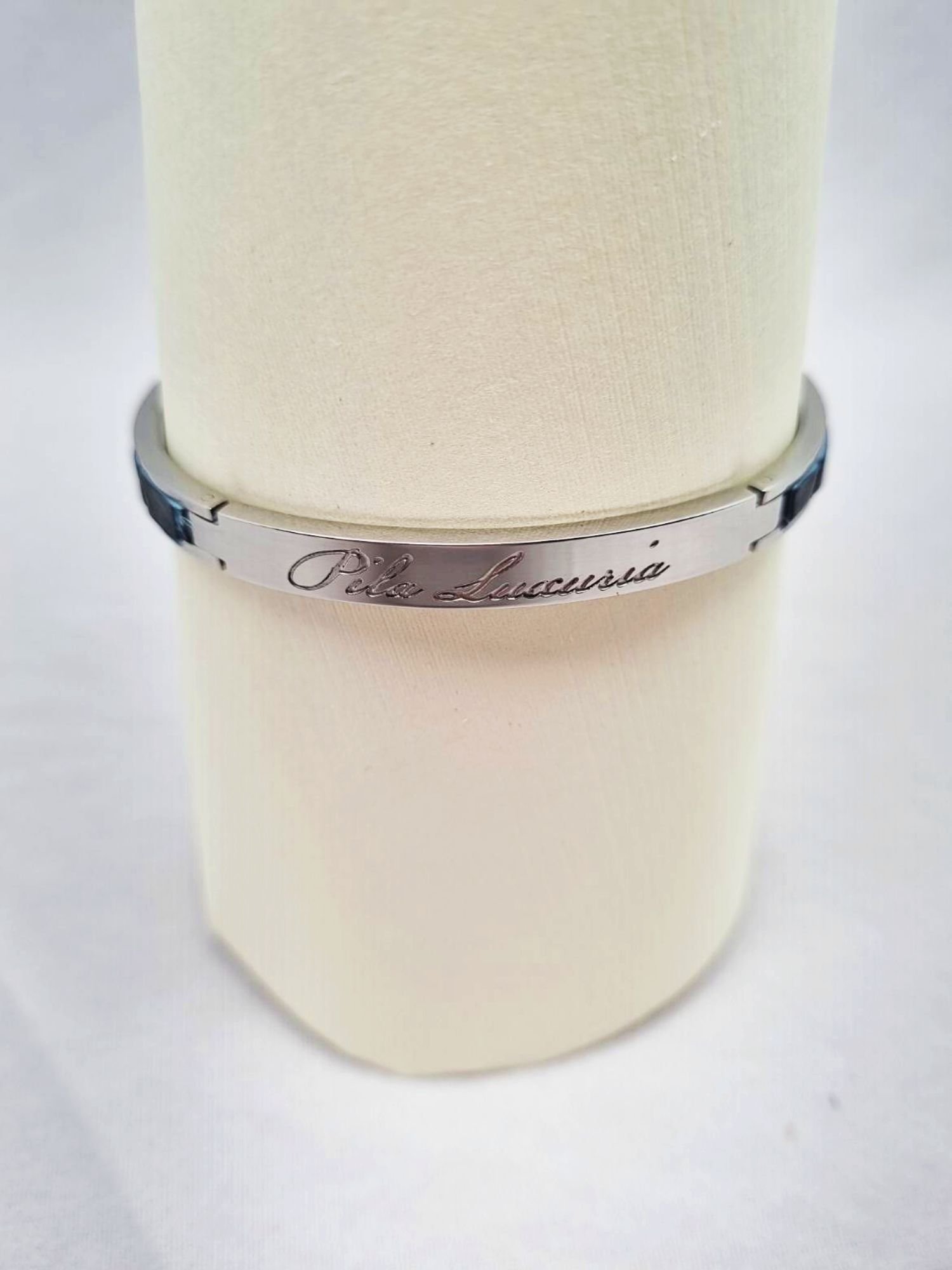 Logo of a luxury denim blue crocodile clasp bracelet, made by Pila Luxuria in Canada.