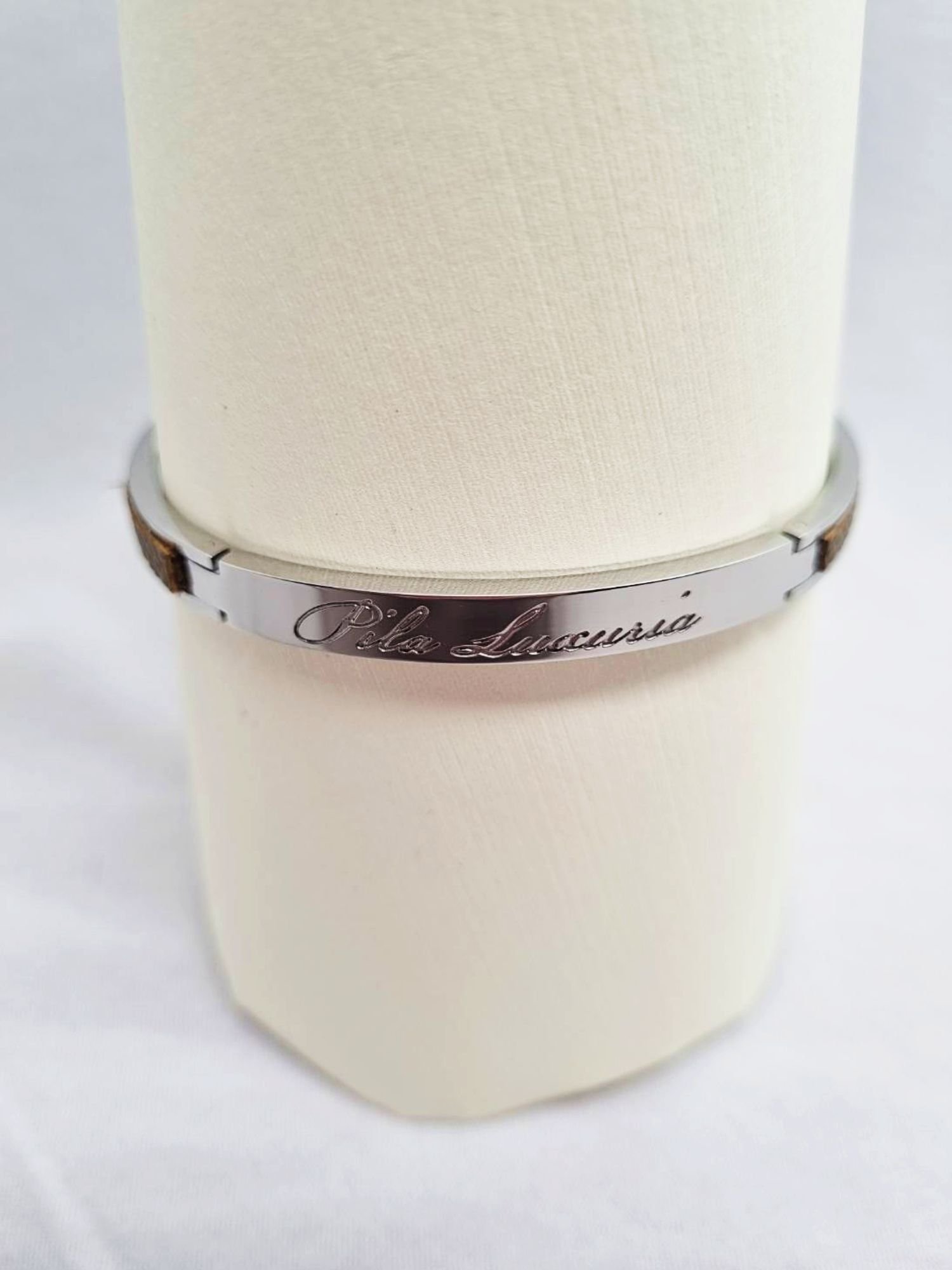 Stainless steel bracelet with etoupe epsom leather inlay and Pila Luxuria script.