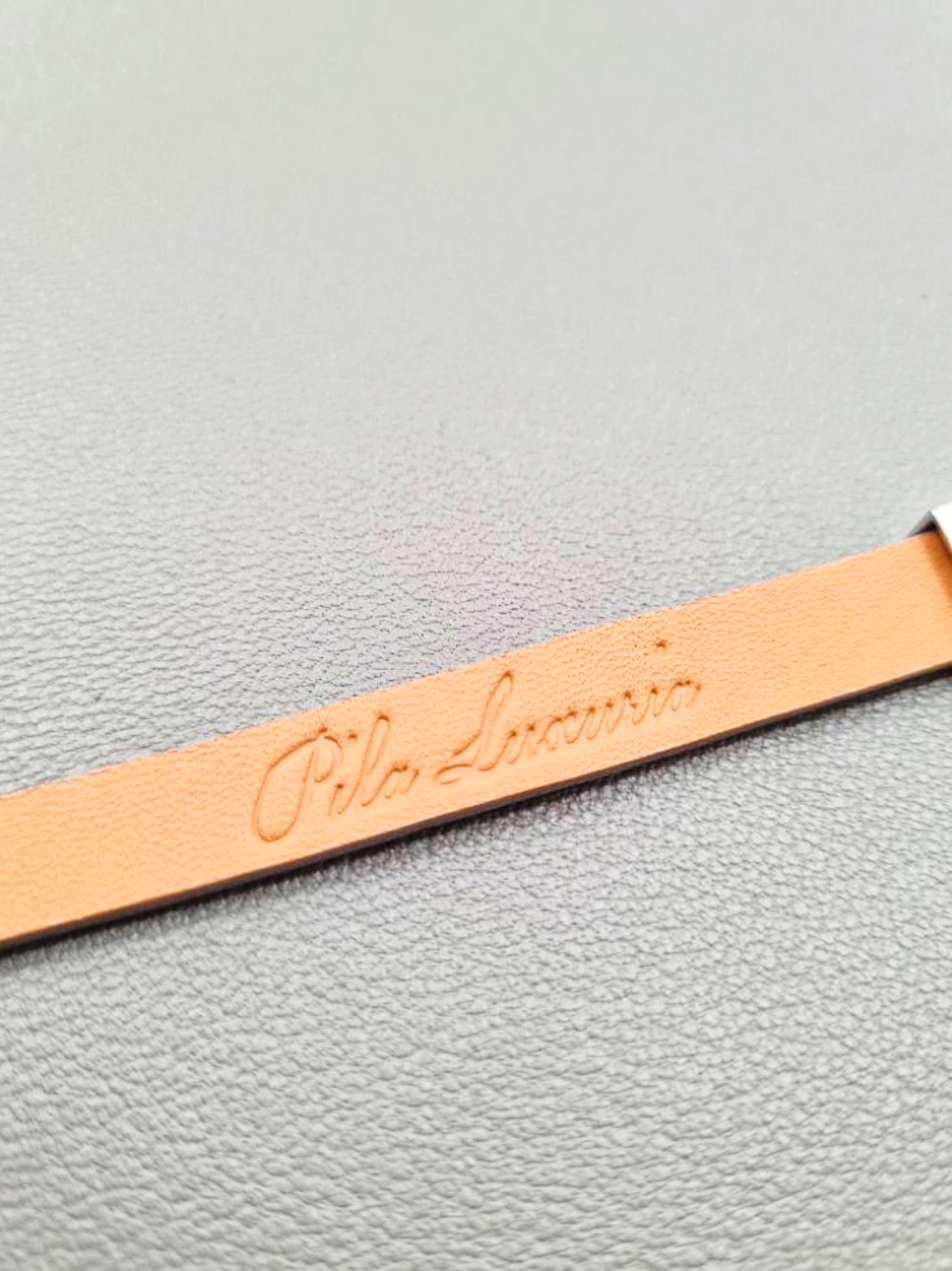 Logo of a luxury grey crocodile clasp bracelet, made by Pila Luxuria in Canada.