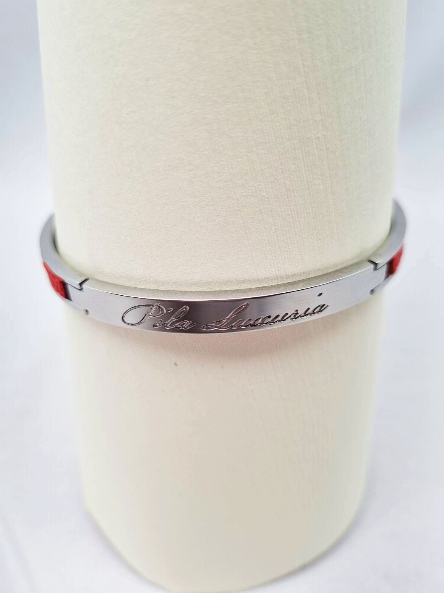 Logo of a luxury red epsom clasp bracelet, made by Pila Luxuria in Canada.