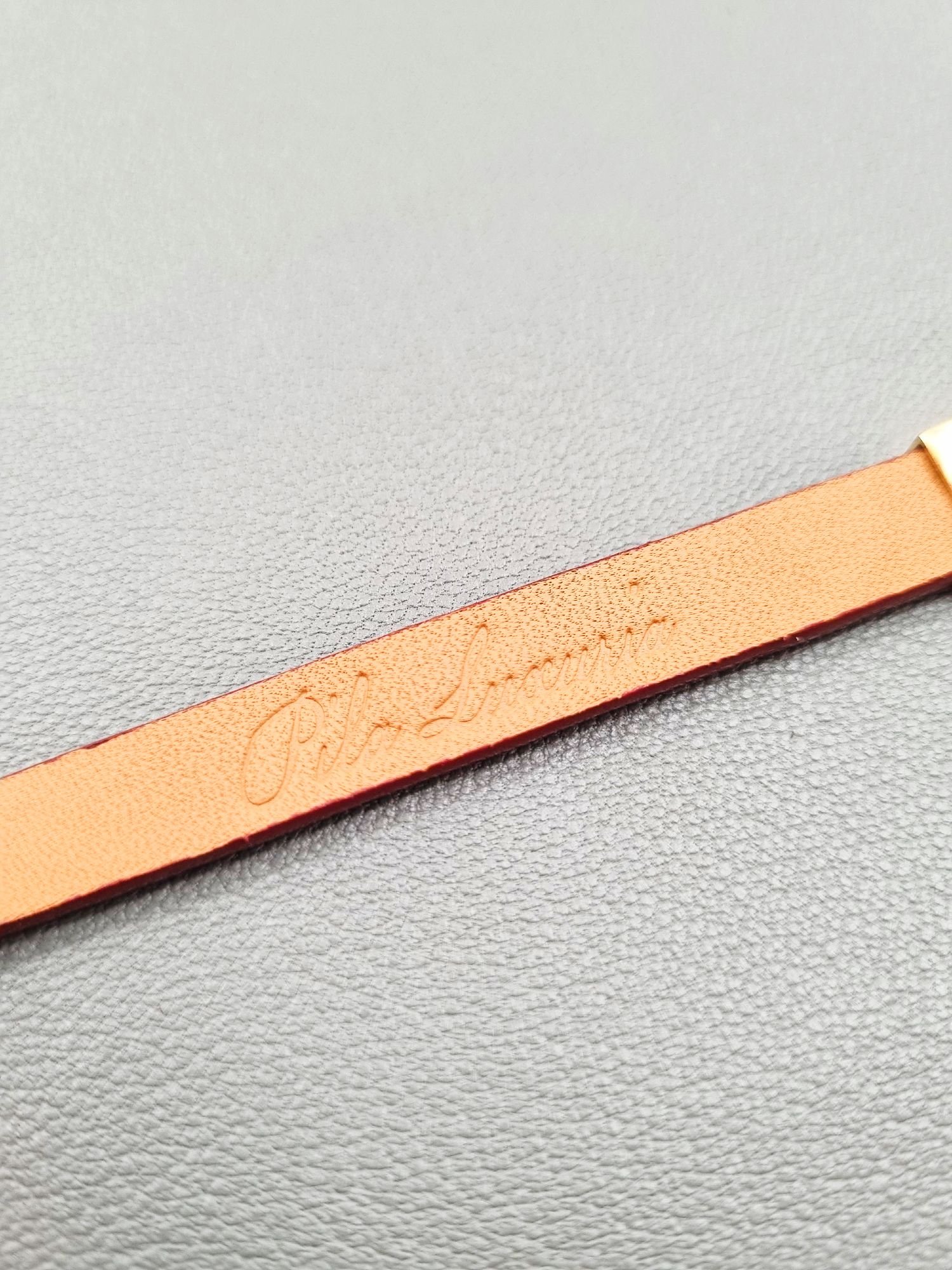 Embossed logo of a luxury red epsom leather bracelet with a magnetic clasp, made by Pila Luxuria in Canada.