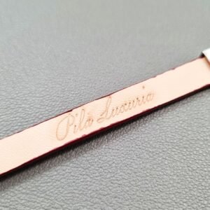 Embossed logo of a luxury red goatskin leather bracelet with a magnetic clasp, made by Pila Luxuria in Canada.