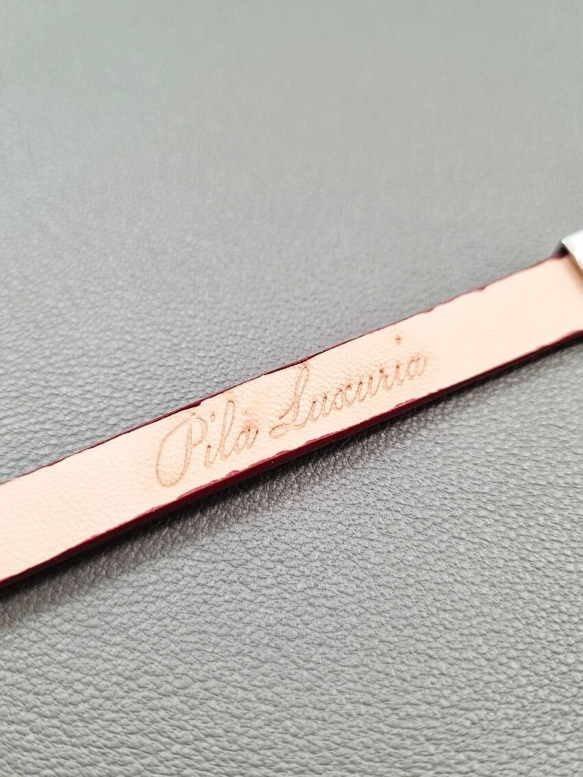 Embossed logo of a luxury red goatskin leather bracelet with a magnetic clasp, made by Pila Luxuria in Canada.