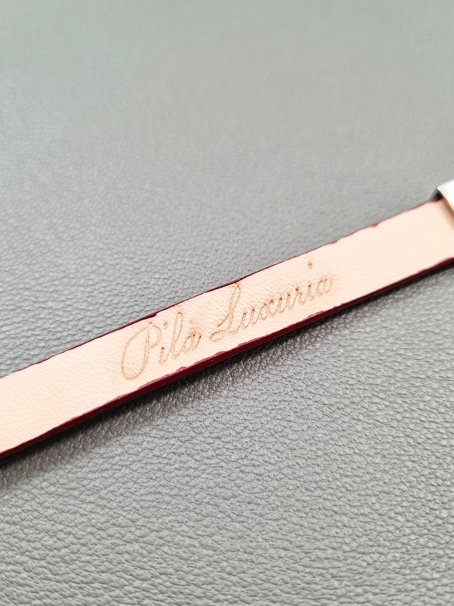 Embossed logo of a luxury red goatskin leather bracelet with a magnetic clasp, made by Pila Luxuria in Canada.